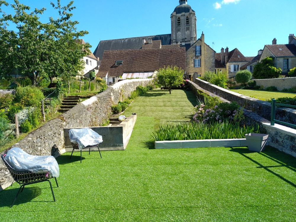 Jardin en pelouse synthétique terminé, vue sur le village